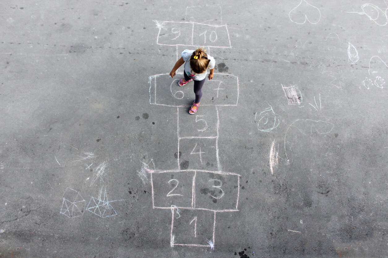 Niña jugando a la rayuela en el recreo escolar.