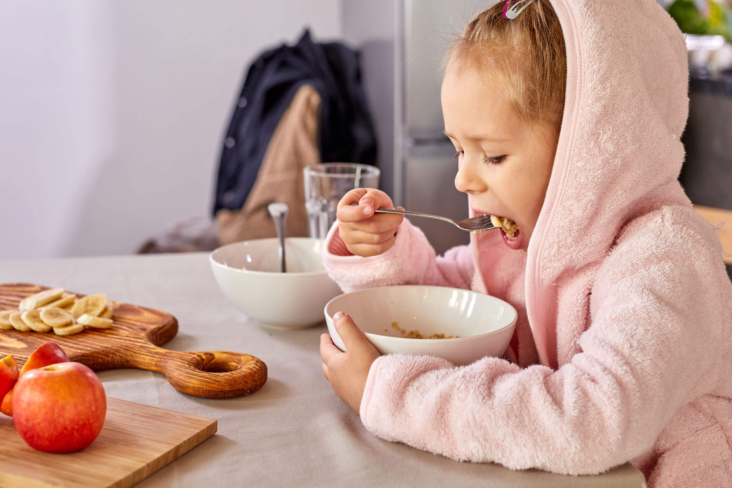 Bambina che mangia farina d'avena e frutta per uno spuntino.