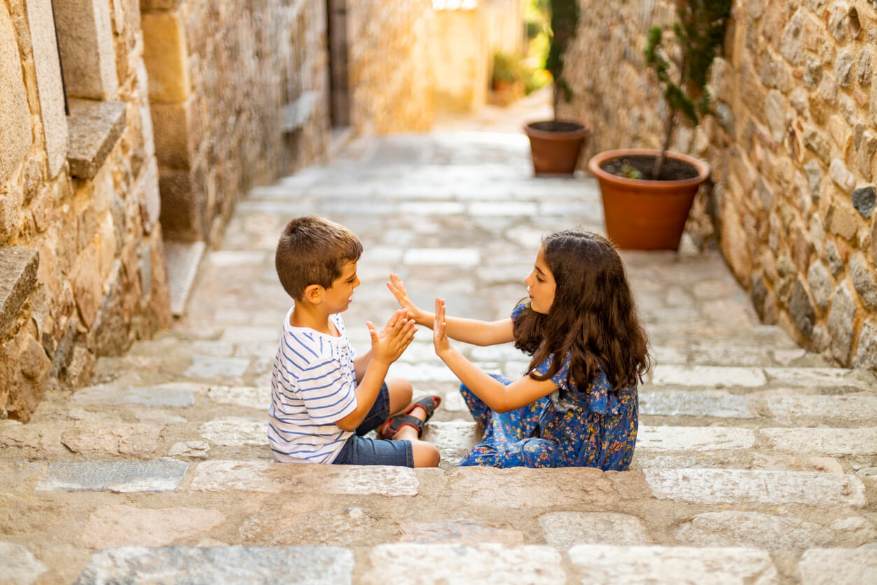 Niña y niño jugando a las palmas en la calle.
