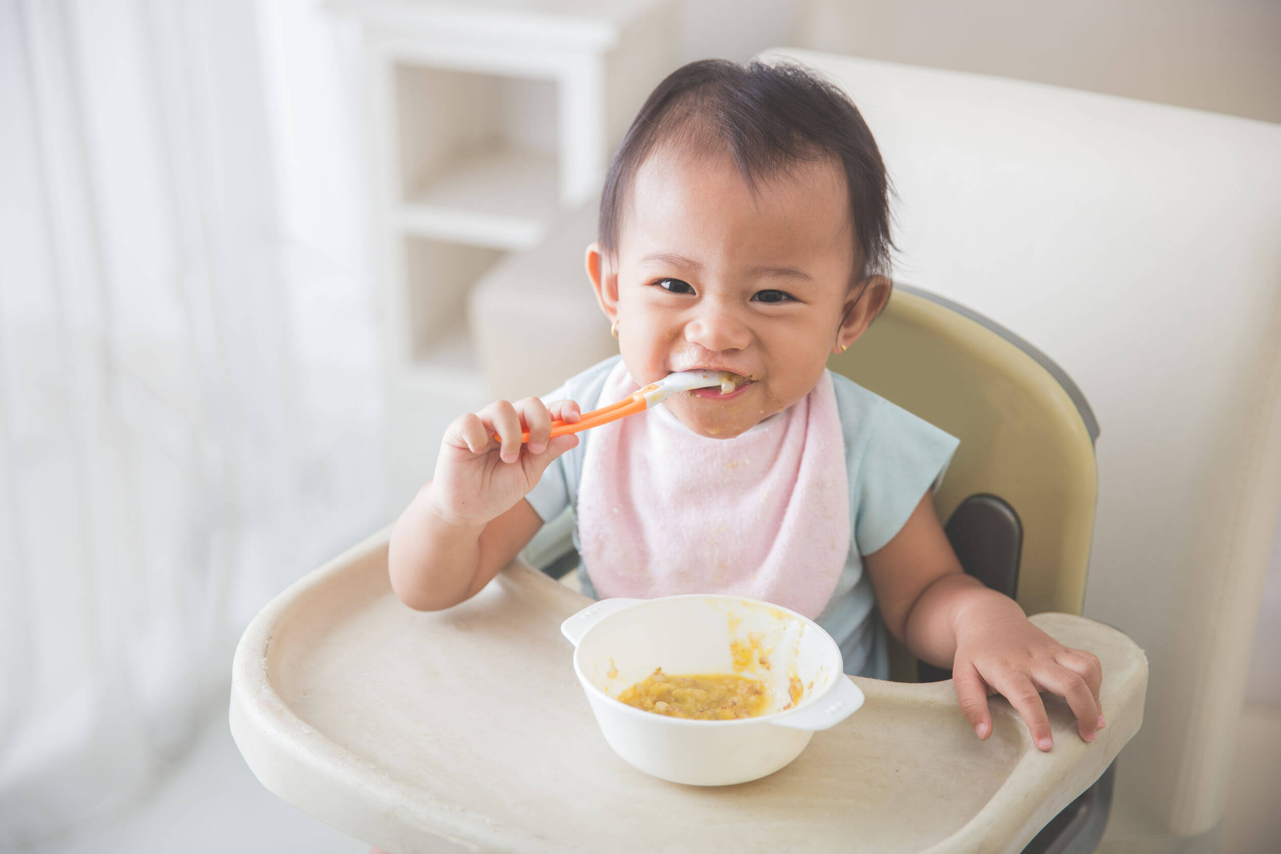 Een baby eet met zijn lepel