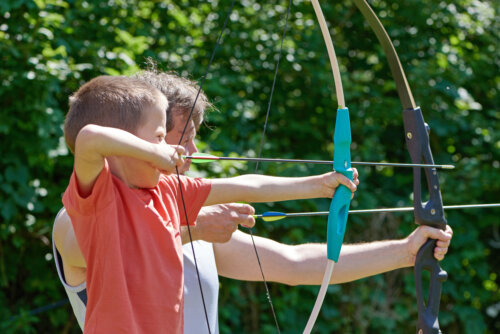 Niño practicando tiro con arco con su entrenador.