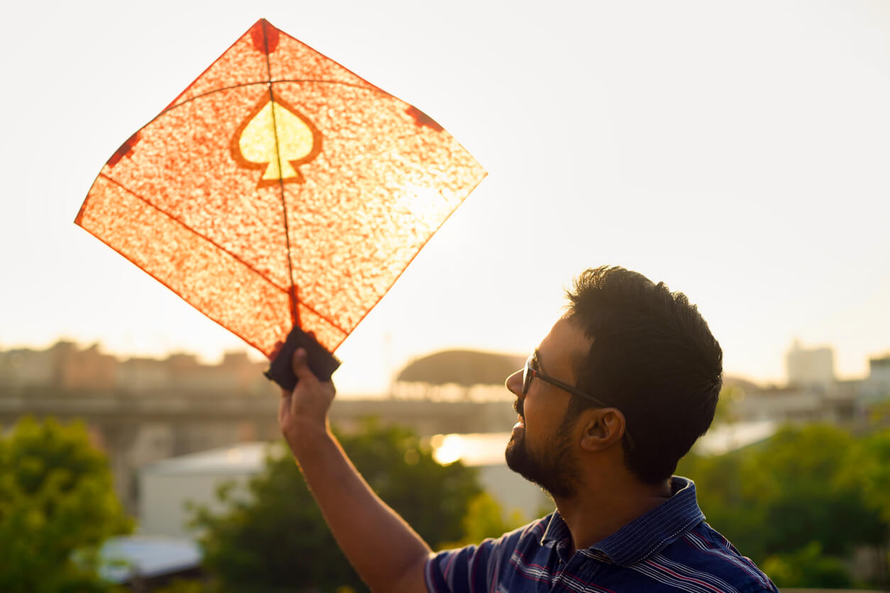 A man holding up a homemade kite.