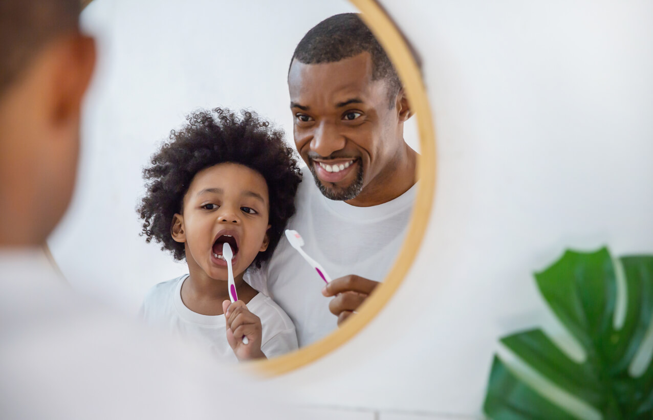 Padre con su hijo enseñando a su hijo a cepillarse los dientes y los diferentes cepillos de dientes para niños.