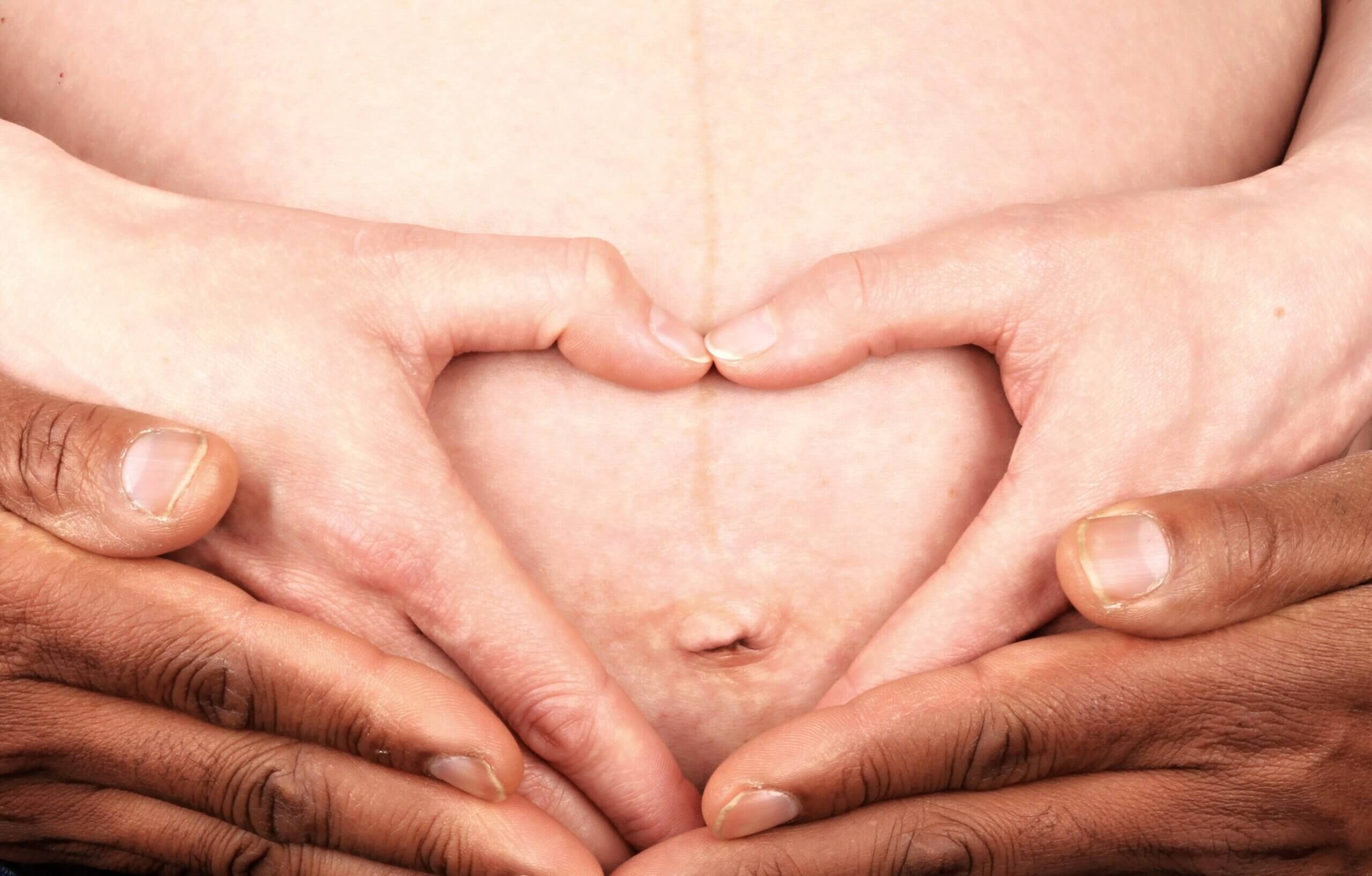 Mains en forme de coeur sur le ventre d'une femme enceinte.