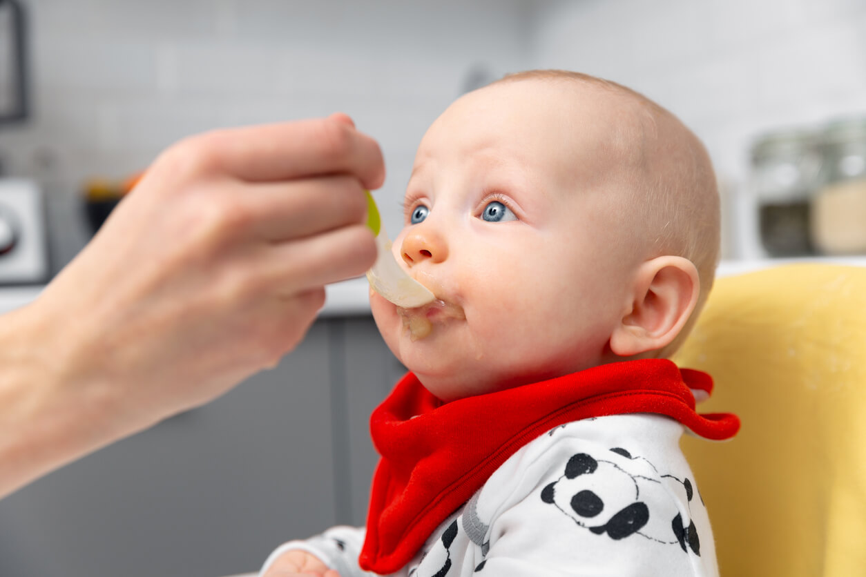 Bebé comiendo papillas de frutas para merendar.