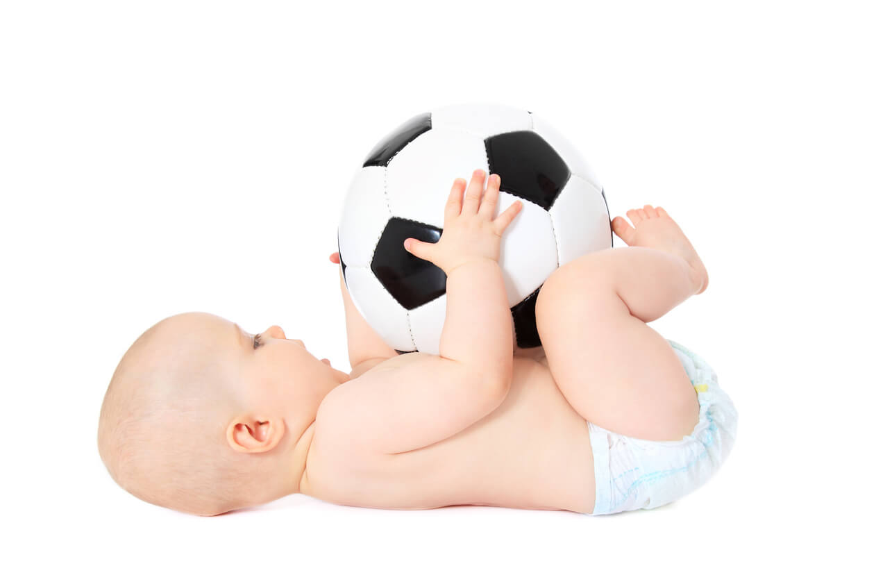 A baby holding a soccer ball.
