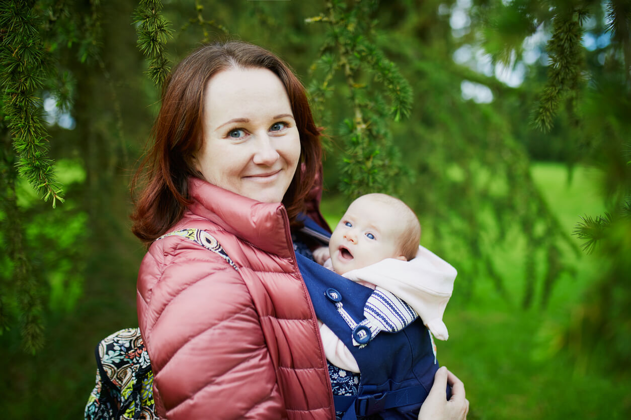 Madre usando una mochila de porteo ergonómico.