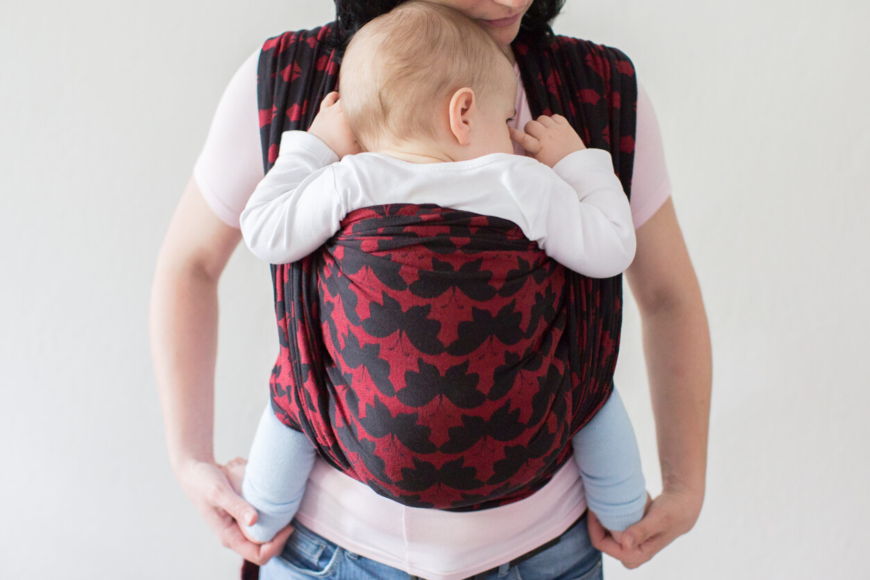 Mère portant une écharpe pour bébé.