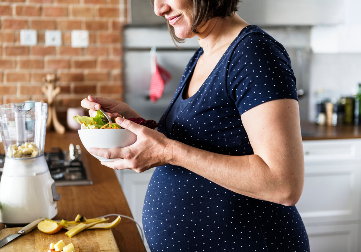 Mujer embarazada comiendo durante el tercer trimestre.