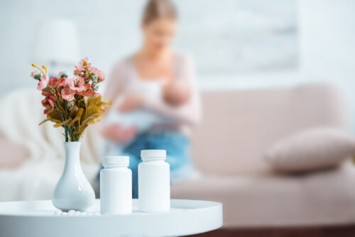 Mujer tomando antibióticos mientras da lactancia materna a su hijo.