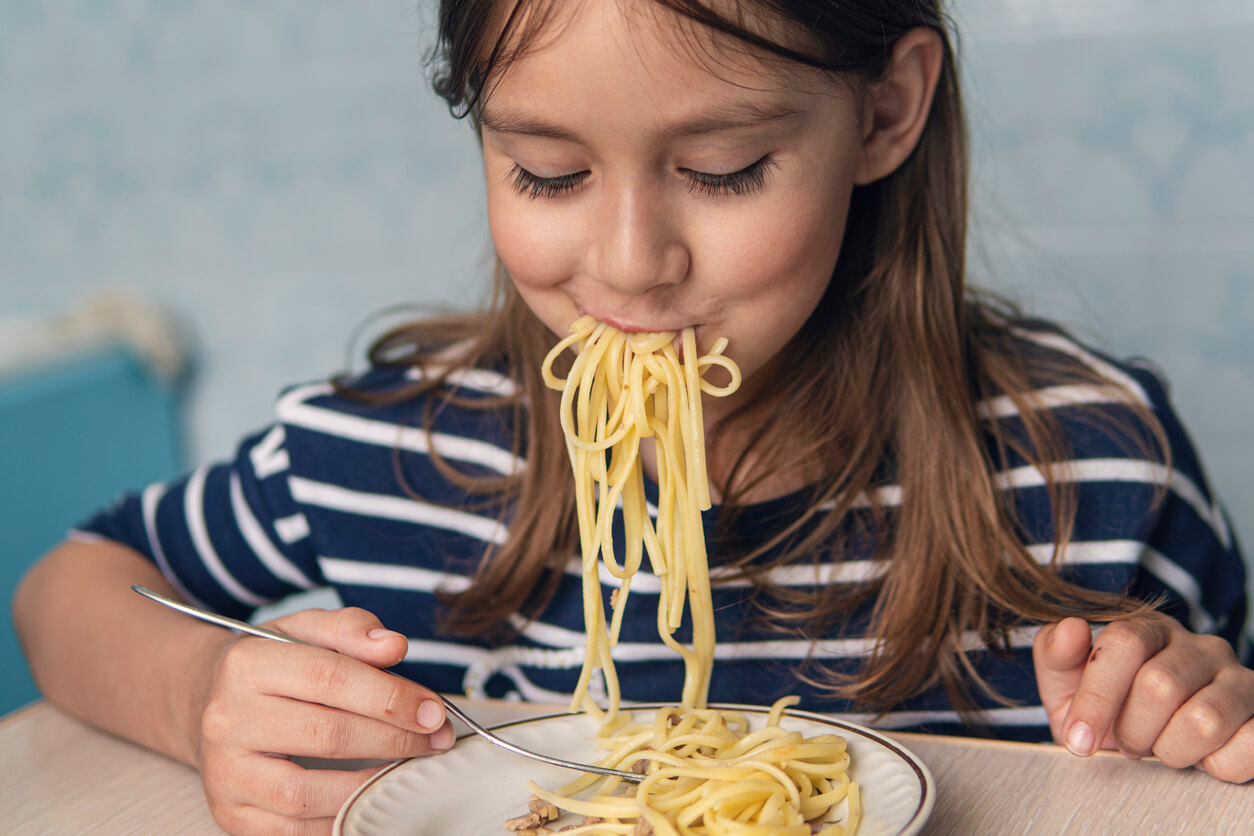 Une jeune fille qui mange des spaghettis;