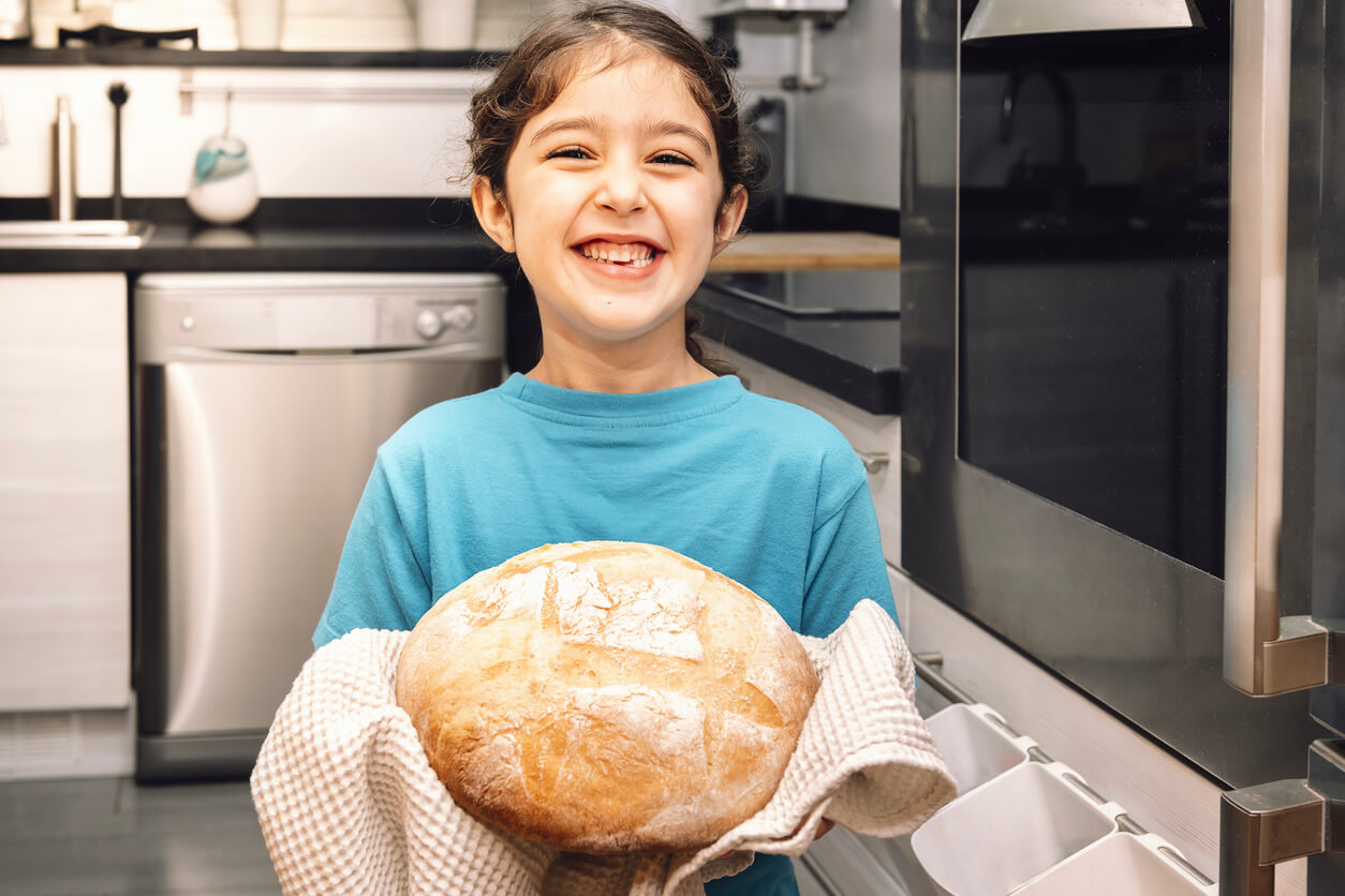 Une jeune fille avec un pain frais dans les mains.