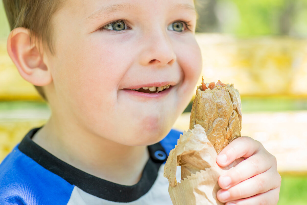 Ett barn som tar en tugga från en smörgås.