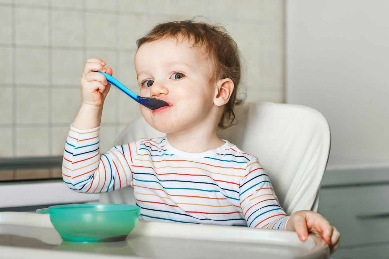 A toddler eating in a high chair.