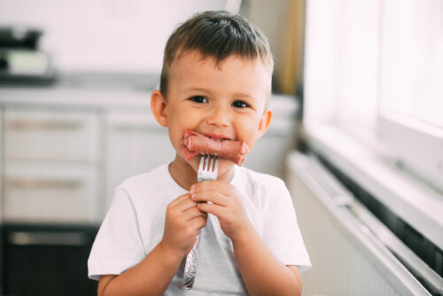 Niño comiéndose una salchicha.