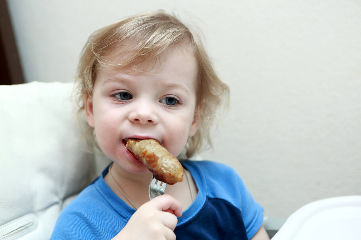 Niño comiendo salchichas son saber que son peligrosas.