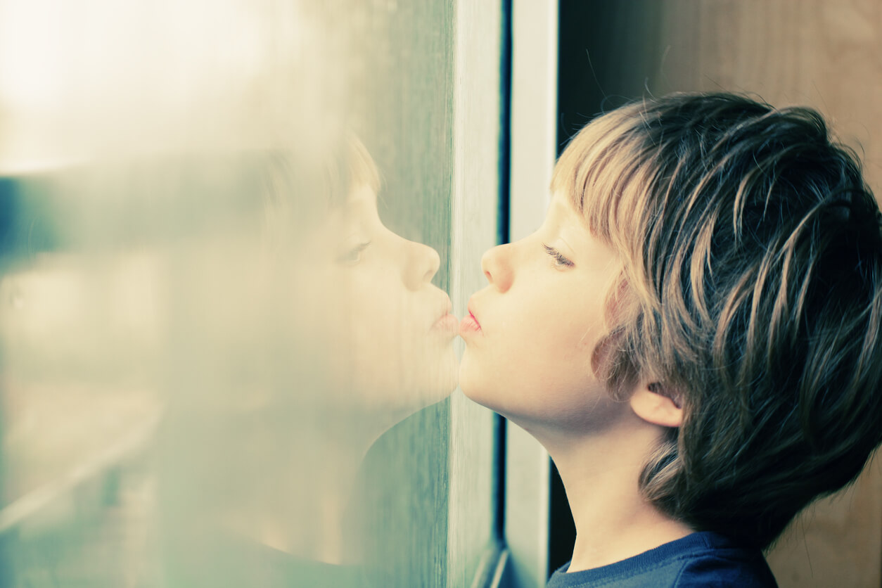 Garçon autiste regardant par la fenêtre.