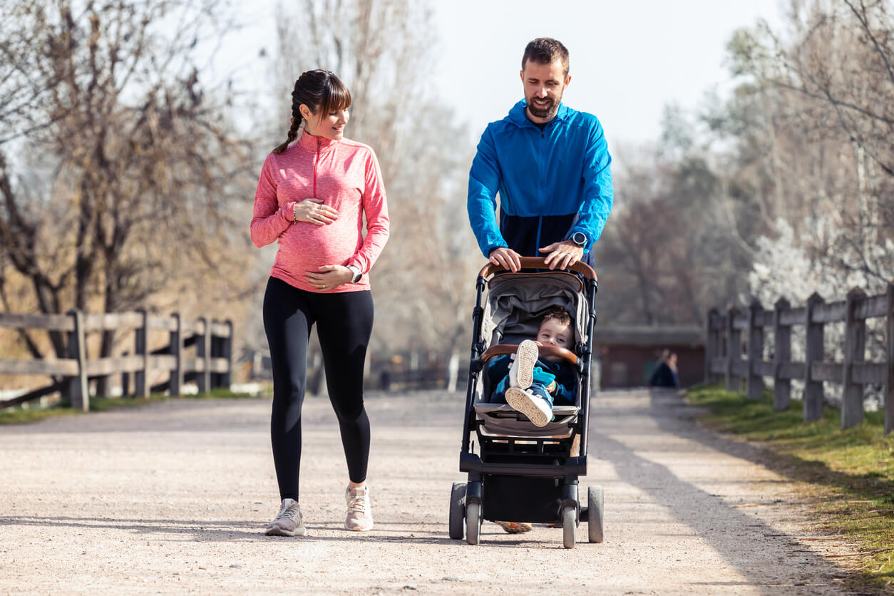Pareja practicando deporte con su hijo en el carrito.