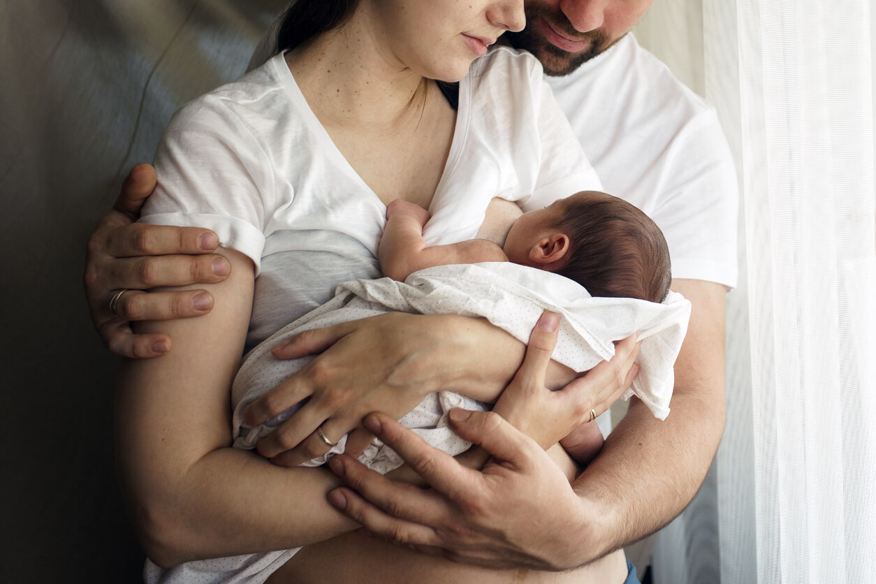 Padres con su bebé recién nacido mientras mama teniendo en cuenta las características del estómago del bebé.