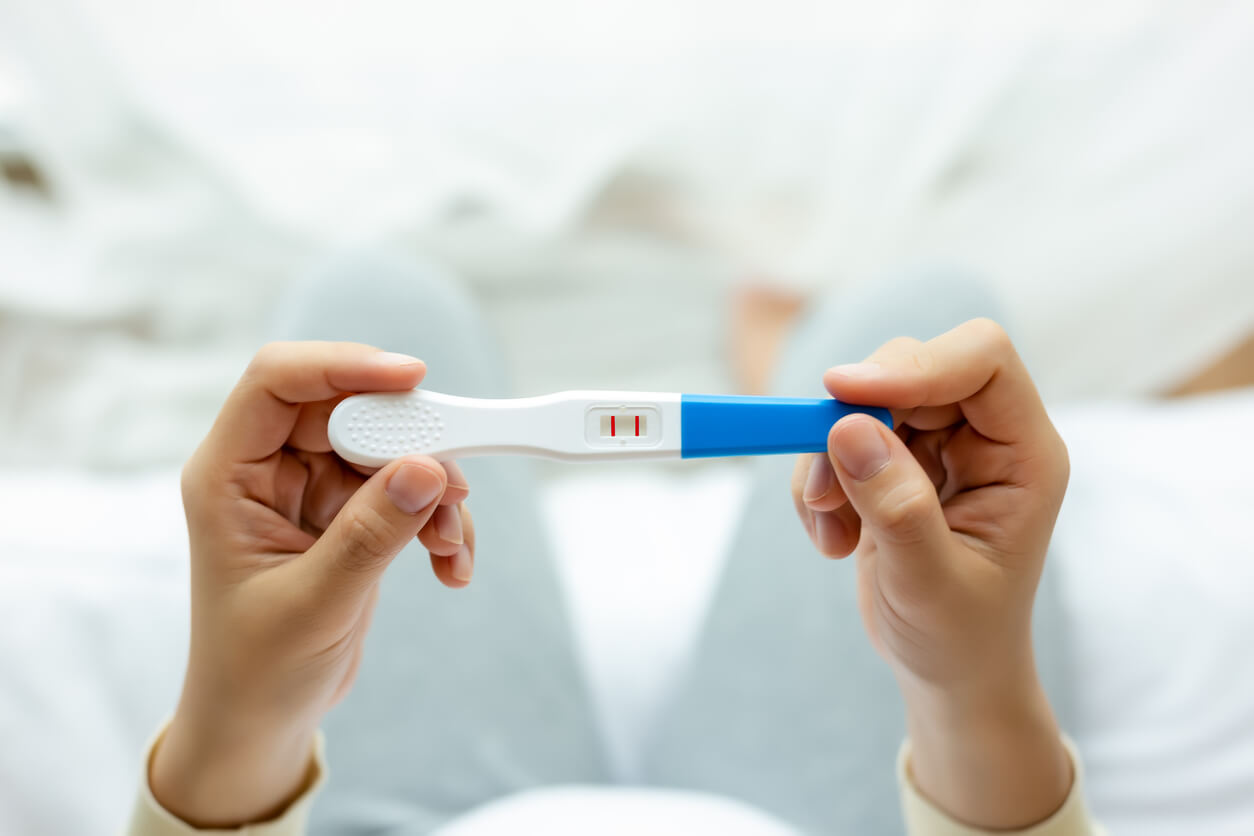 A woman looking at a positive pregnancy test.