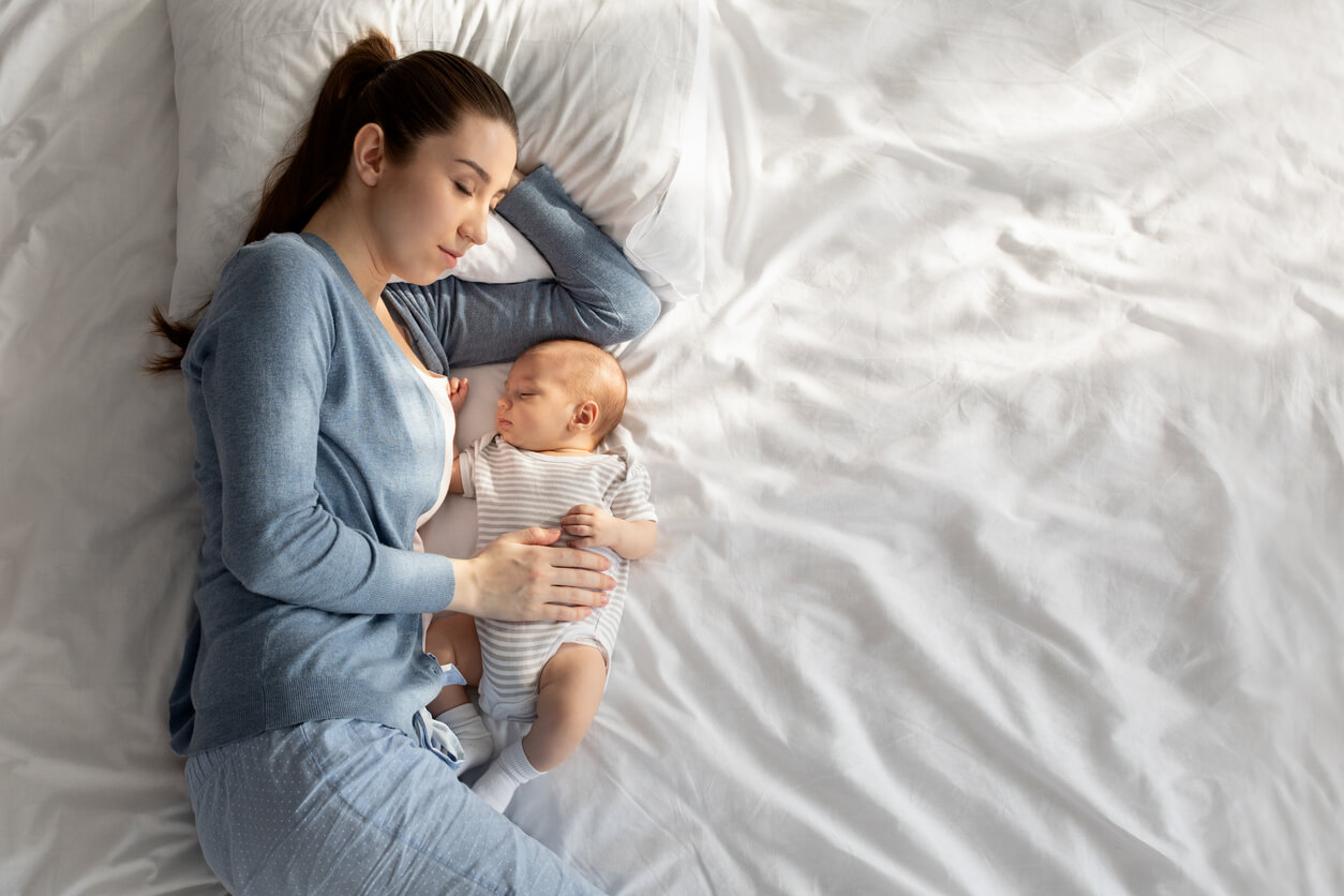 A mother co-sleeping and sleeping with her baby.