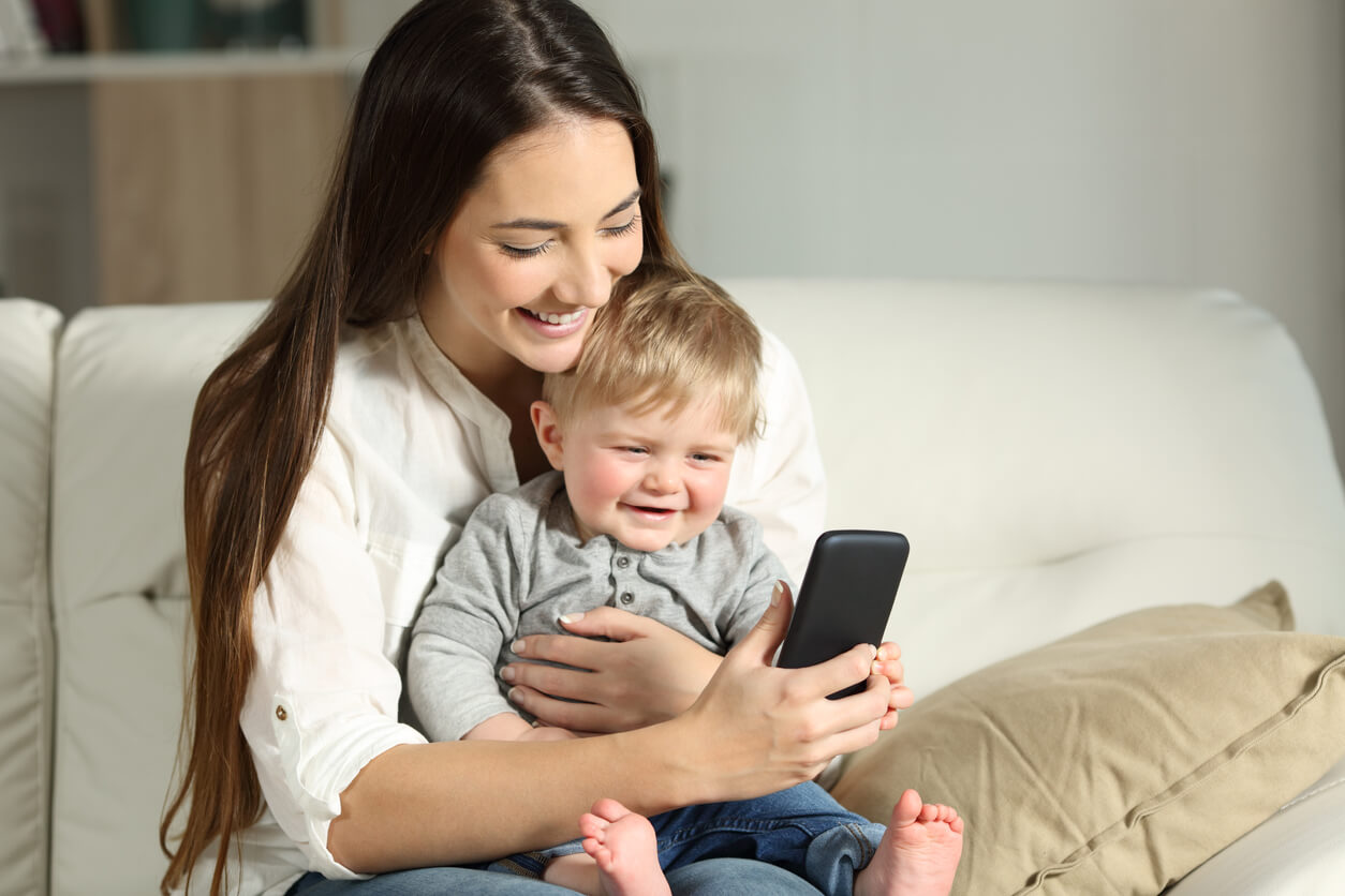 A mother and baby looking at a smartphone.