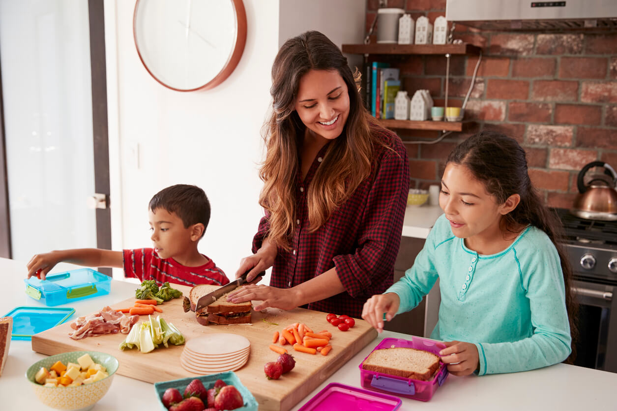 Madre con sus hijos en la cocina preparando platos saludables con todos los nutrientes necesarios.