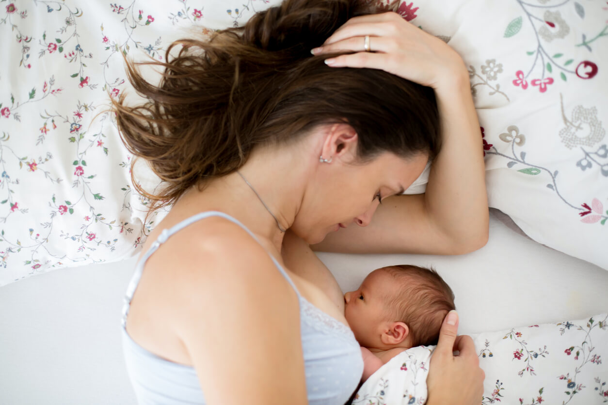 A mother breastfeeding her baby in bed.