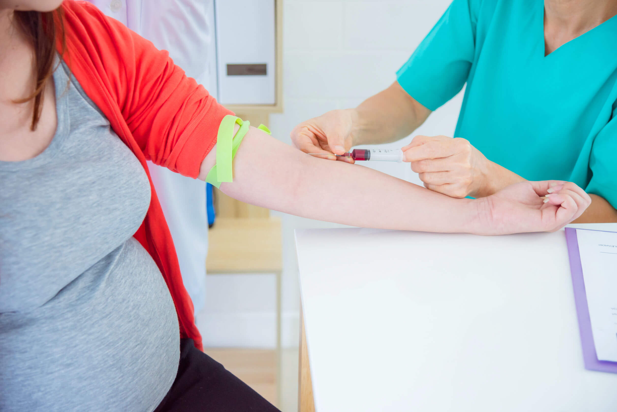 A doctor performing a blood draw on a pregnant woman.