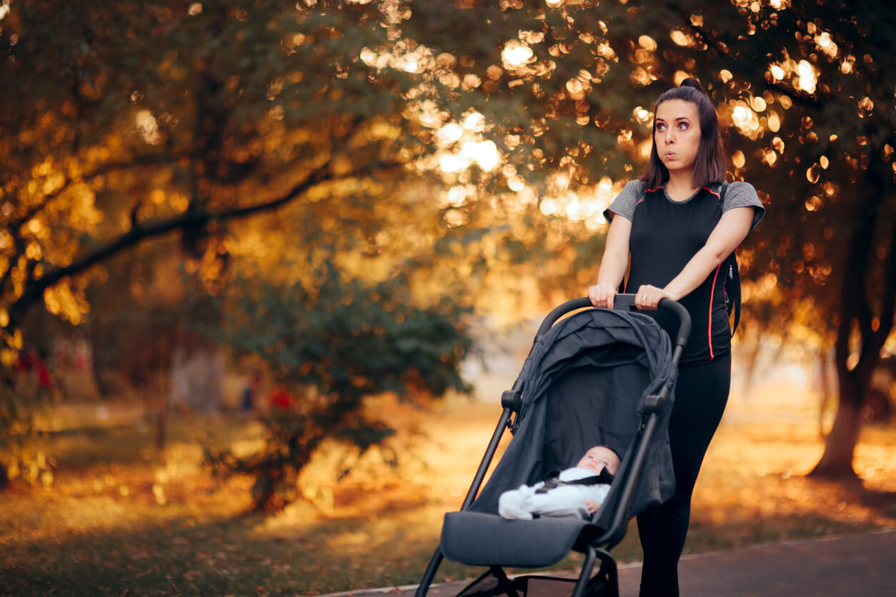 Une femme qui marche avec son bébé dans la poussette.