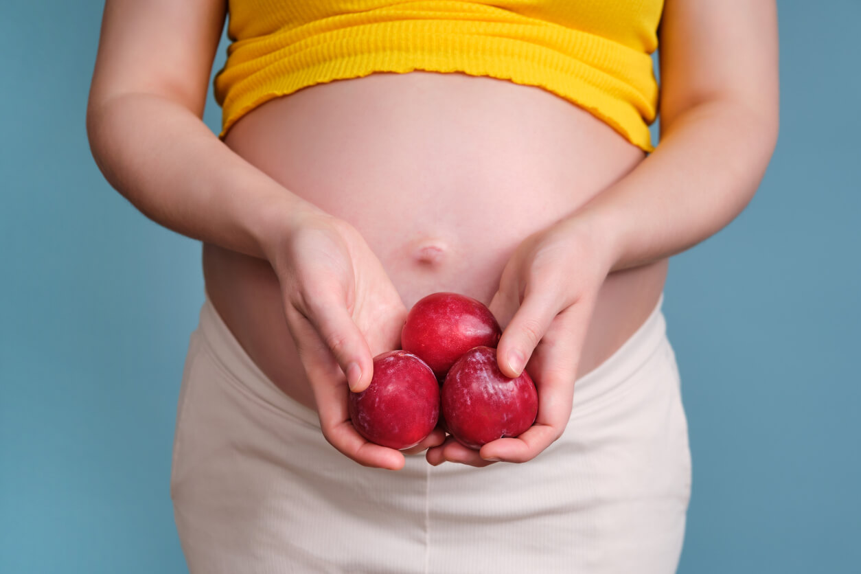 Mujer comiendo ciruelas para combatir el estreñimiento en el embarazo.