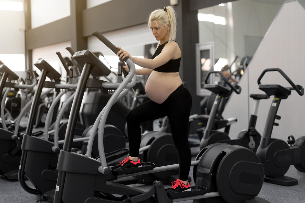 Mujer embarazada haciendo ejercicio en una bicicleta elíptica.