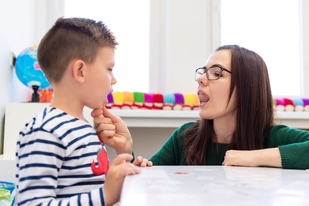 Enfant avec une orthophoniste faisant des exercices de déglutition.