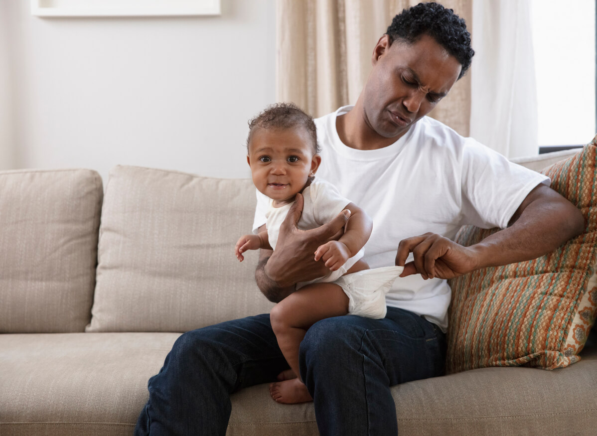 Padre mirando el pañal de su hijo porque se ha hecho caca.