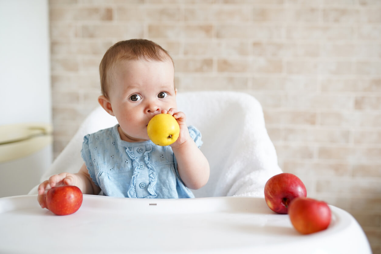 En baby plukker opp epler.