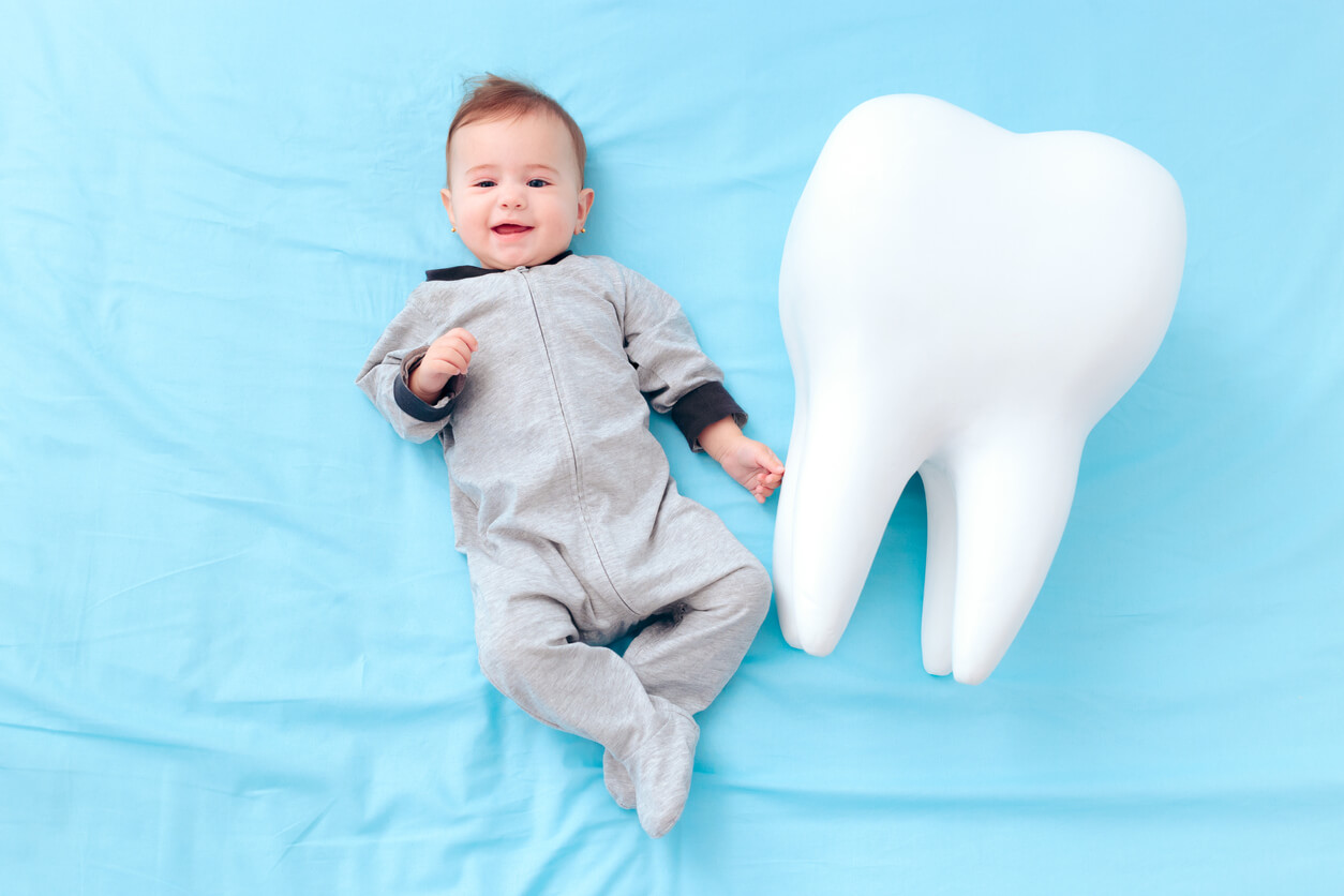 Un bébé à côté d'une dent géante.