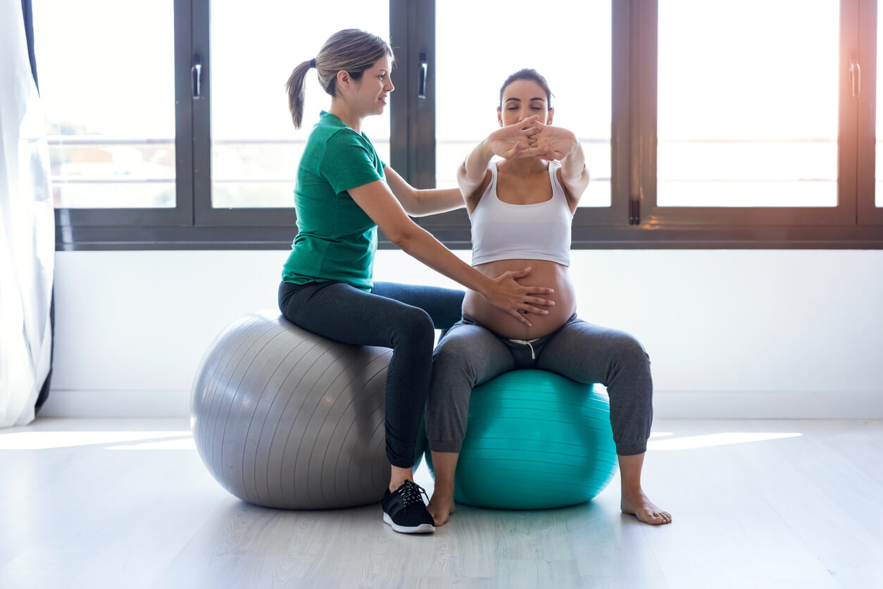 A pregnant woman doing pelvic exercises with an exercise ball.