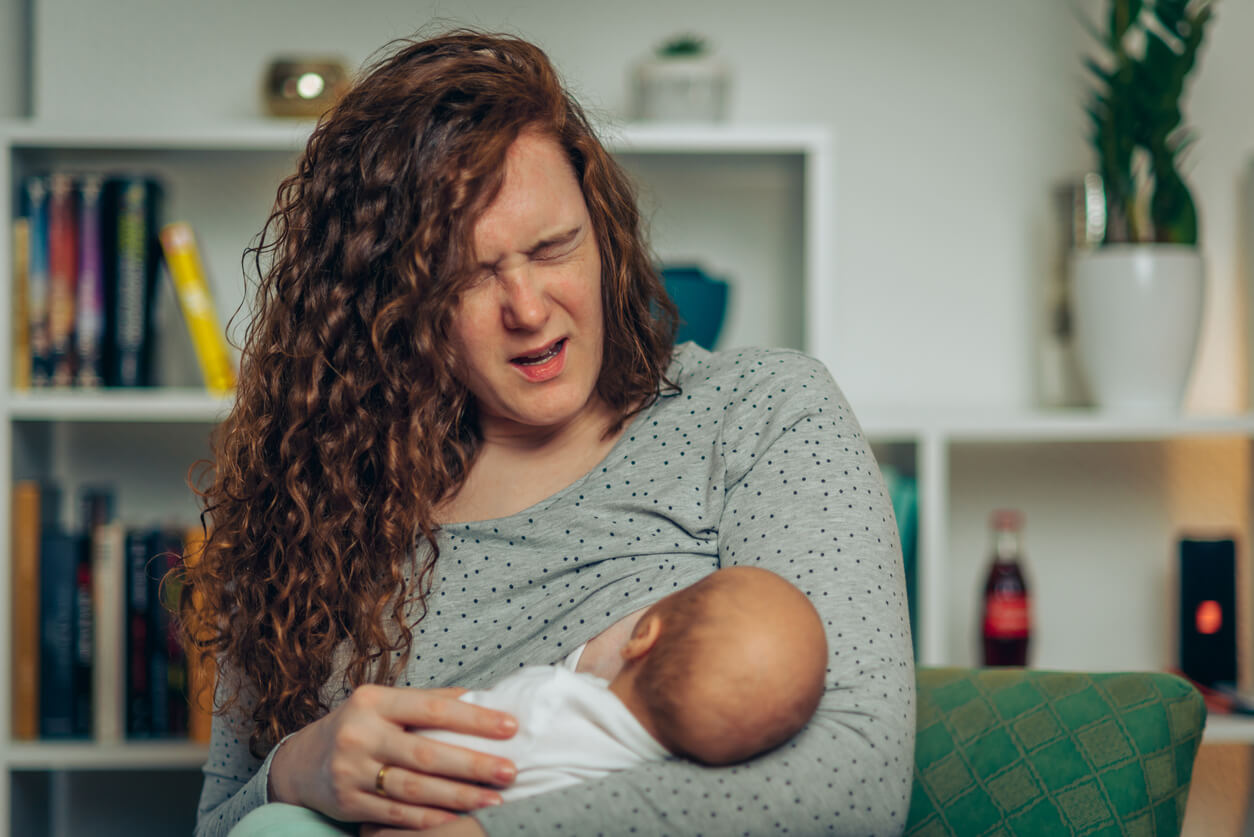 A woman experiencing pain as her newborn nurses.