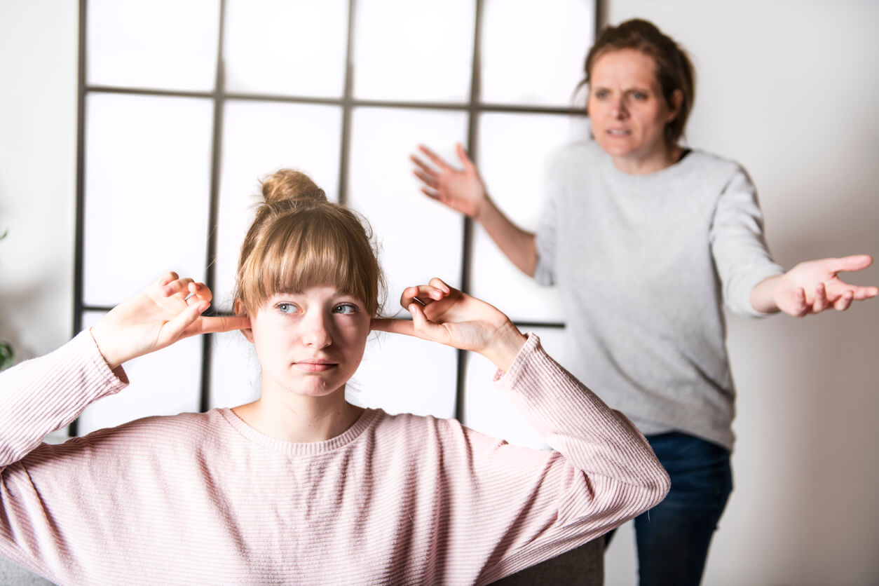 Teini-ikäinen tyttö ei huomioi nalkuttavaa äitiään.