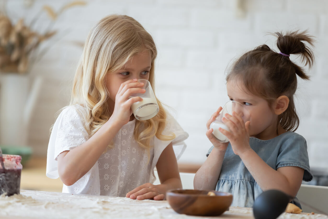 Niñas merendando un vaso de leche según la cantidad adecuada para su edad.