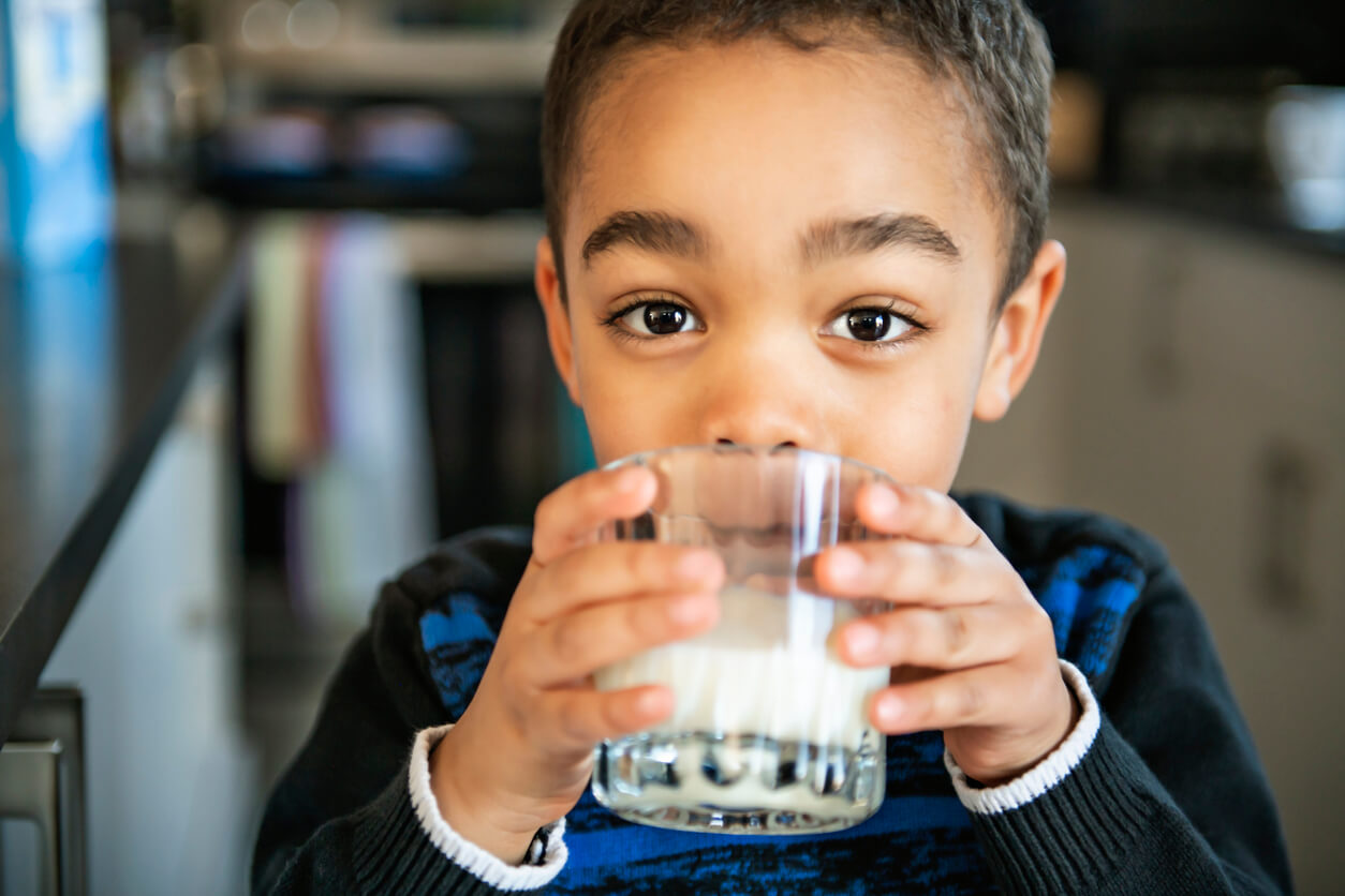 A young boy drinking a glass of milk.
