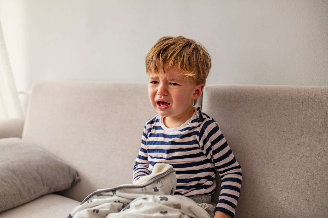 Un enfant qui pleure sur le canapé.