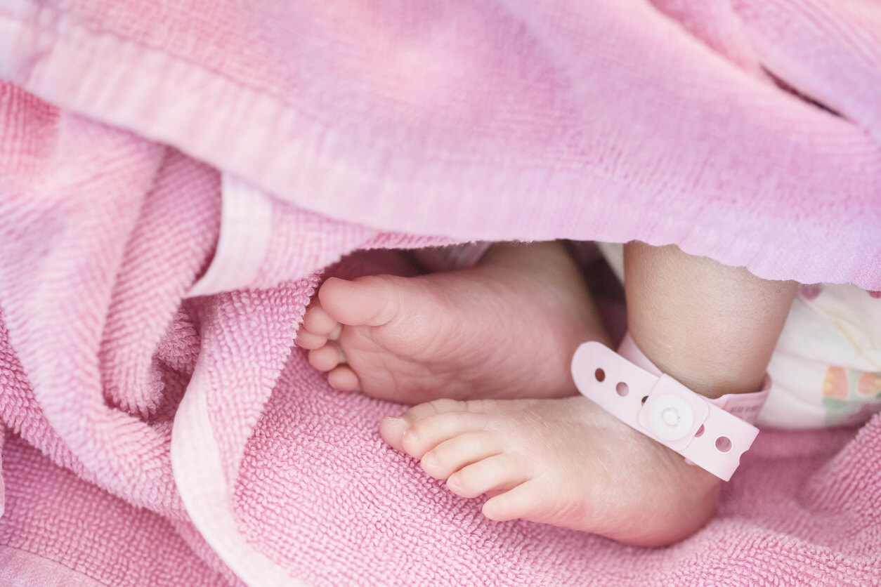 A newborn baby's feet sticking out from a pink towel.