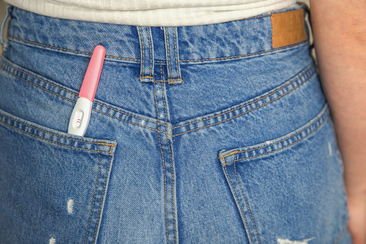 mulher com teste de gravidez positivo no bolso da calça jeans