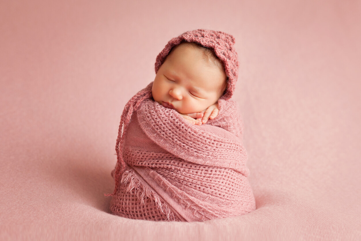 A newborn baby wrapped in a pink blanket.