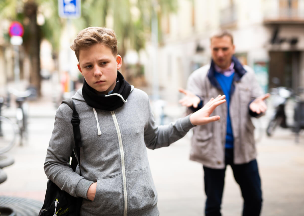 A teenage boy angrily walking away from his dad.