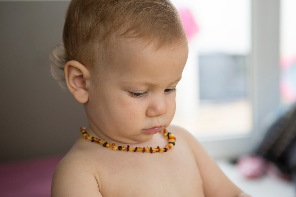Un bébé avec un collier d'ambre autour du cou. 