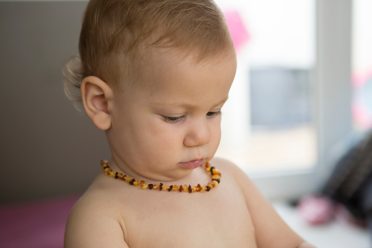 Un bébé avec un collier d'ambre autour du cou.