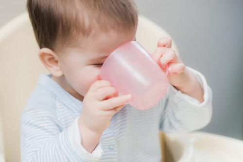 bebe sentado silla toma bebe solo agua vaso taza asas