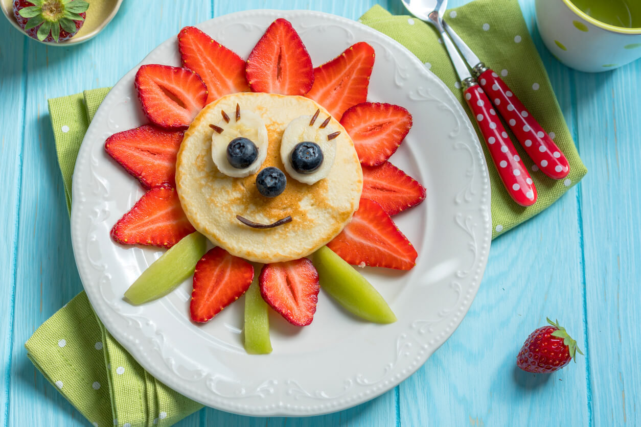 A pancake decorated with fruit to look like a flower.